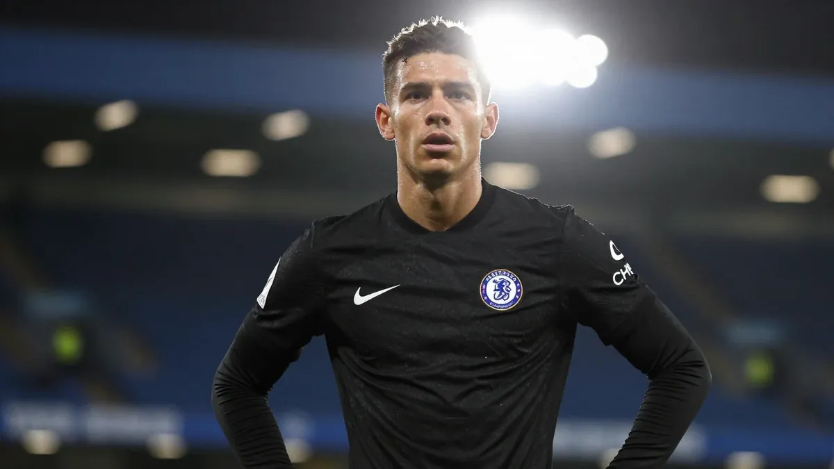 Floodlight rim light: A 25-year-old midfielder in Chelsea's all-black kit stands intense and focused, head-and-shoulders...